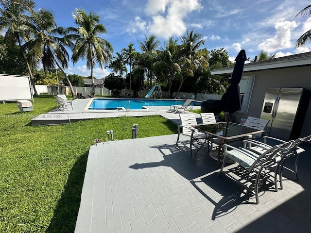 view of swimming pool with a water slide, a patio area, and a lawn