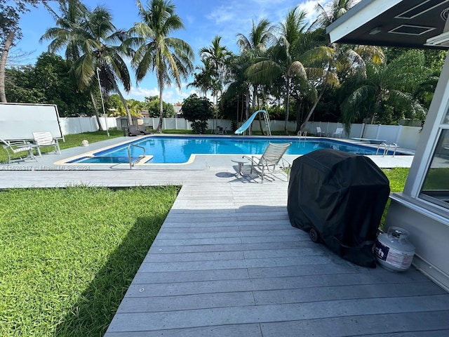 view of pool with grilling area, a deck, and a water slide