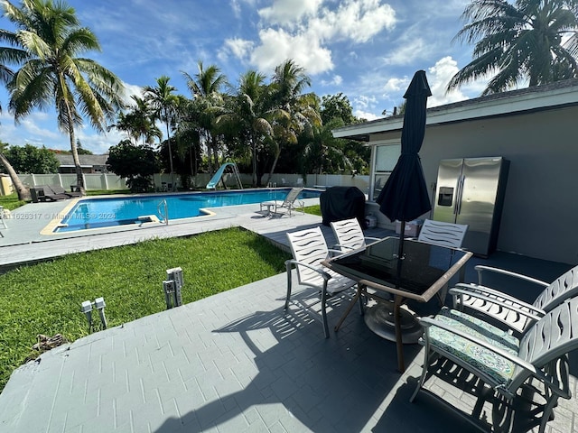 view of pool with a patio area, a lawn, and a water slide