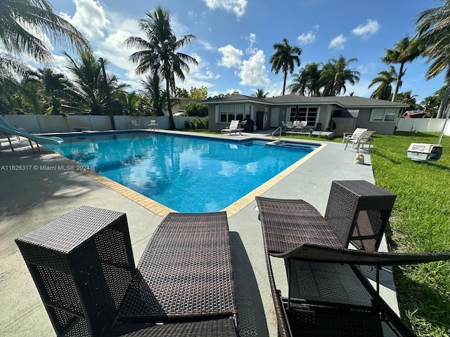 view of swimming pool featuring a yard, a water slide, and a patio area