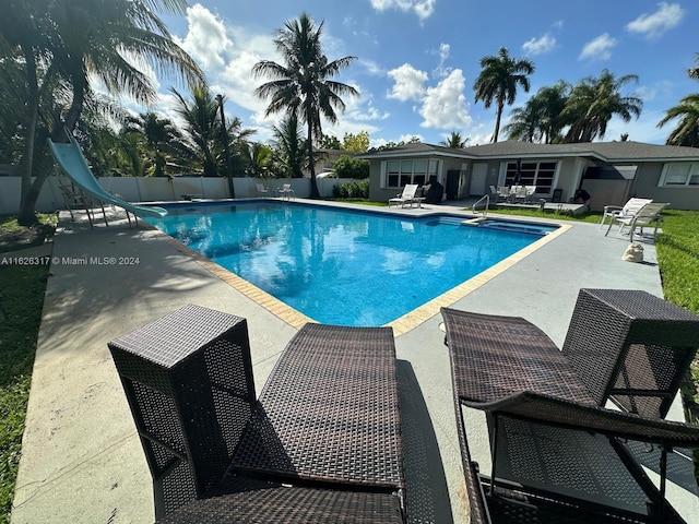 view of pool with a water slide and a patio area