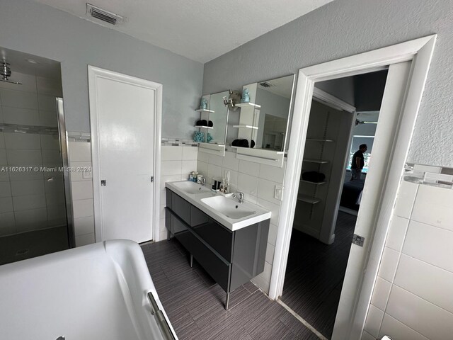 bathroom featuring tile patterned floors, double sink vanity, backsplash, and tile walls