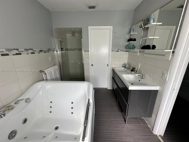 bathroom featuring a shower with shower door, vanity, tile walls, and tile patterned floors