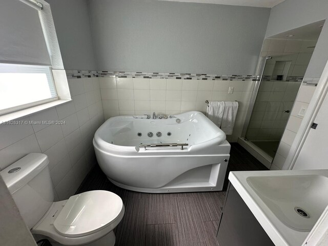 bathroom featuring toilet, an enclosed shower, tile patterned flooring, and tile walls