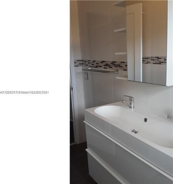 bathroom with tile walls, vanity, and decorative backsplash