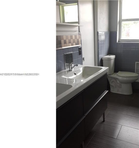 bathroom featuring vanity, toilet, and tile walls