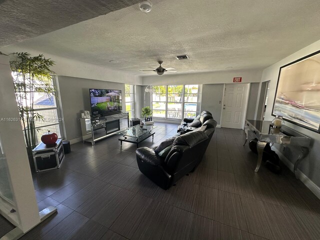 living room with ceiling fan and a textured ceiling