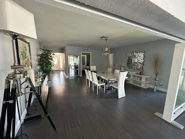 dining space with an inviting chandelier and a textured ceiling