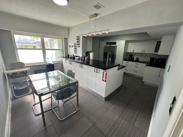 kitchen with a textured ceiling, white cabinets, and stainless steel fridge with ice dispenser