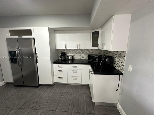 kitchen featuring white cabinetry, backsplash, stainless steel fridge, and dark tile patterned flooring