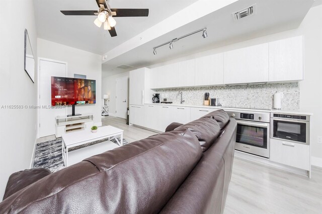 living room with sink, light wood-type flooring, ceiling fan, and track lighting