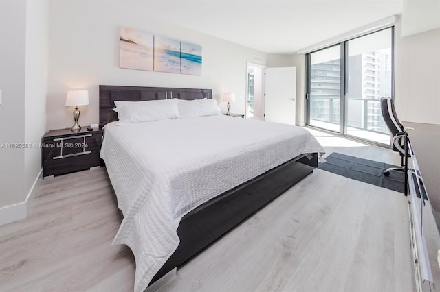 bedroom featuring floor to ceiling windows, access to outside, and light hardwood / wood-style floors