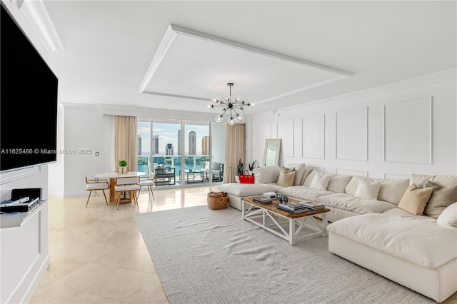 living room with a raised ceiling, a chandelier, ornamental molding, and a decorative wall