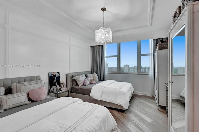 bedroom featuring hardwood / wood-style flooring, a raised ceiling, and a chandelier