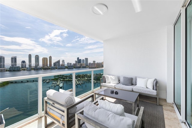 balcony featuring an outdoor living space, a water view, and a city view