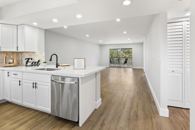 kitchen with light wood-type flooring, sink, dishwasher, kitchen peninsula, and white cabinetry