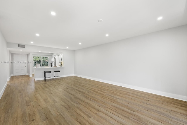 unfurnished living room with sink and light hardwood / wood-style flooring