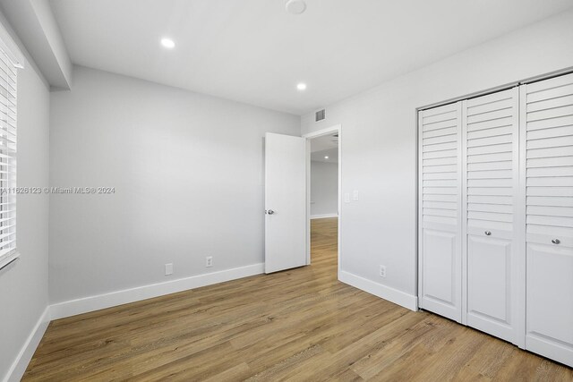 unfurnished bedroom with a closet and light wood-type flooring