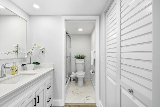 bathroom featuring a shower with shower door, vanity, and toilet