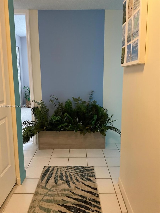 hall featuring a textured ceiling and light tile patterned floors