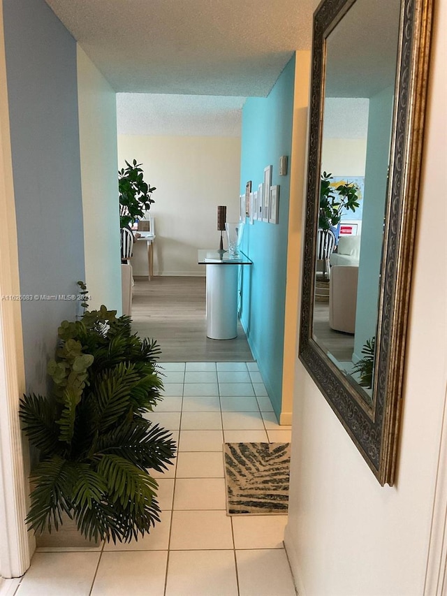 hallway featuring a textured ceiling and light tile patterned floors