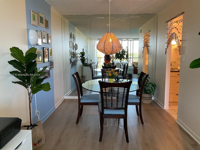 dining room featuring wood-type flooring and a textured ceiling