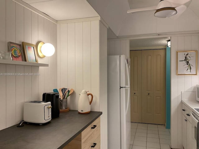 kitchen with wood walls, white appliances, and light tile patterned floors