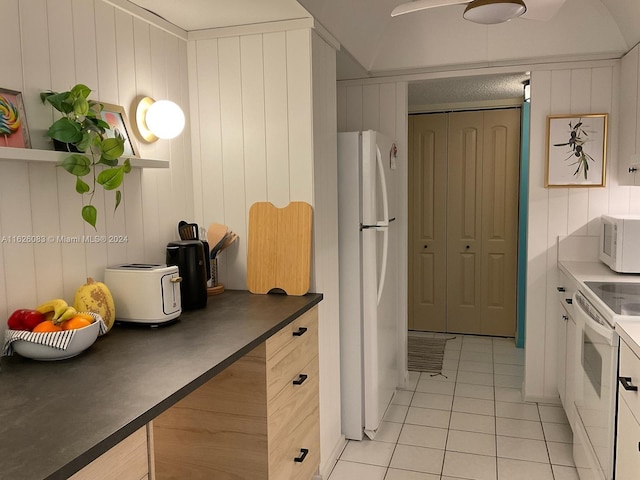 kitchen with white appliances, wooden walls, and light tile patterned flooring