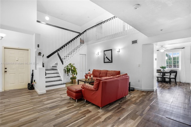 living room with ceiling fan, hardwood / wood-style floors, and a high ceiling