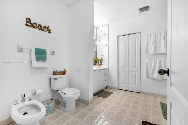 bathroom featuring a bidet, toilet, vanity, and tile patterned flooring