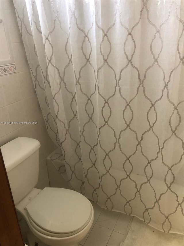 bathroom featuring tile patterned flooring, toilet, and tile walls