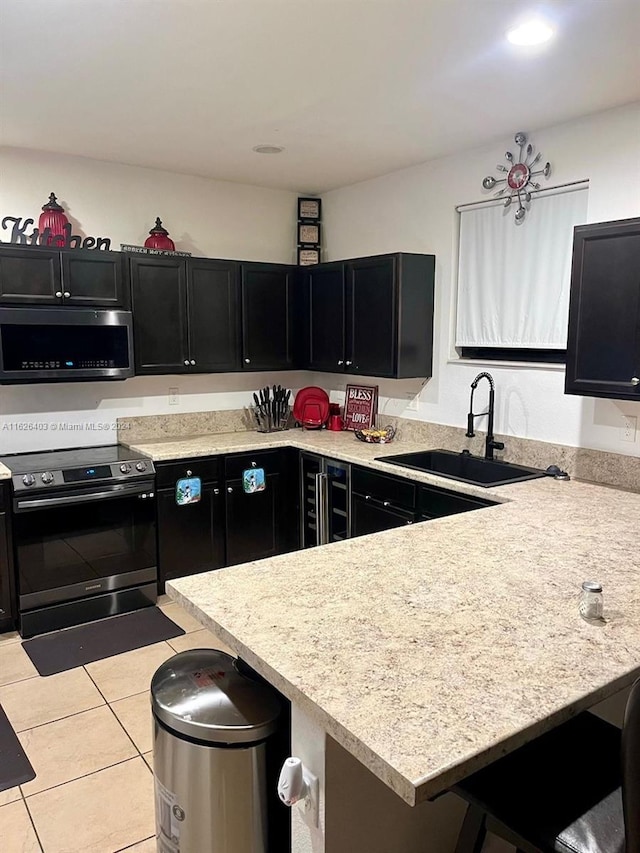 kitchen with a breakfast bar area, sink, appliances with stainless steel finishes, and light tile patterned floors