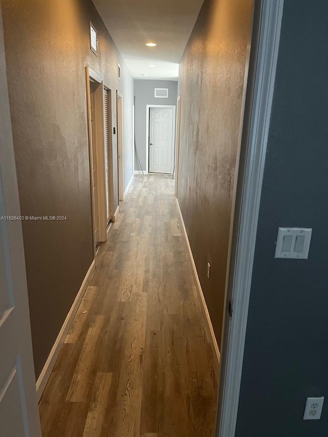 corridor with hardwood / wood-style flooring