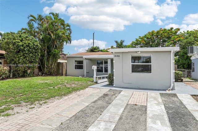 view of front facade featuring a patio, cooling unit, and a front lawn