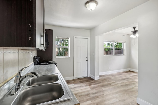 kitchen with a healthy amount of sunlight, sink, dark brown cabinets, and stove