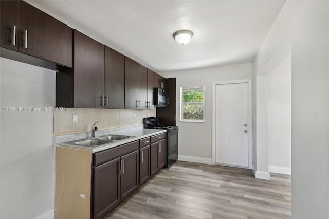 kitchen with dark brown cabinetry, sink, black appliances, and light hardwood / wood-style floors