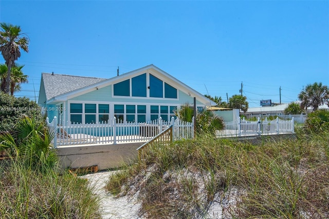 rear view of property featuring a fenced in pool