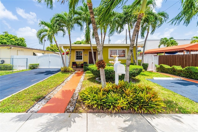 bungalow-style house with aphalt driveway, stucco siding, fence, and a gate