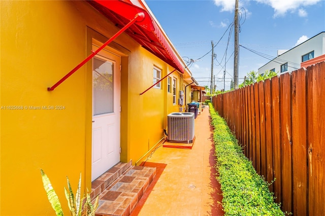 view of side of property with a patio, fence, central AC, and stucco siding