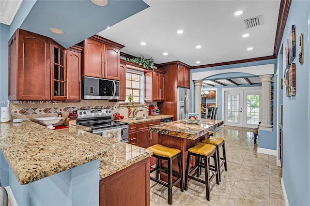 kitchen with backsplash, a kitchen bar, decorative columns, arched walkways, and stainless steel appliances