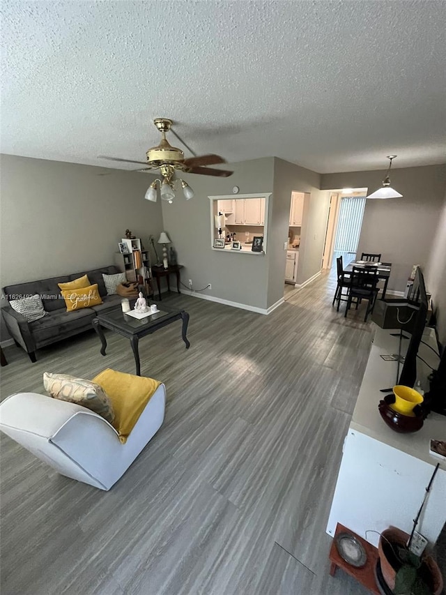 living room with ceiling fan, a textured ceiling, and dark hardwood / wood-style flooring