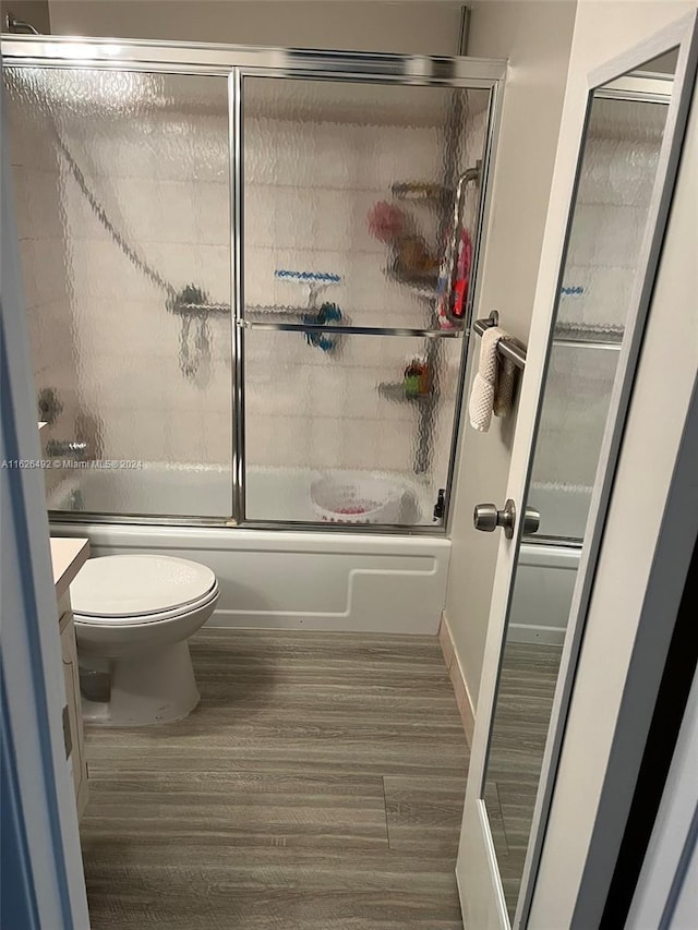 full bathroom with hardwood / wood-style floors, toilet, enclosed tub / shower combo, and vanity