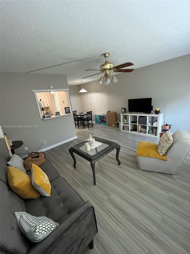 living room with ceiling fan, a textured ceiling, and hardwood / wood-style flooring