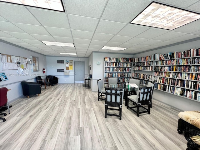 home office with a drop ceiling and light wood-type flooring