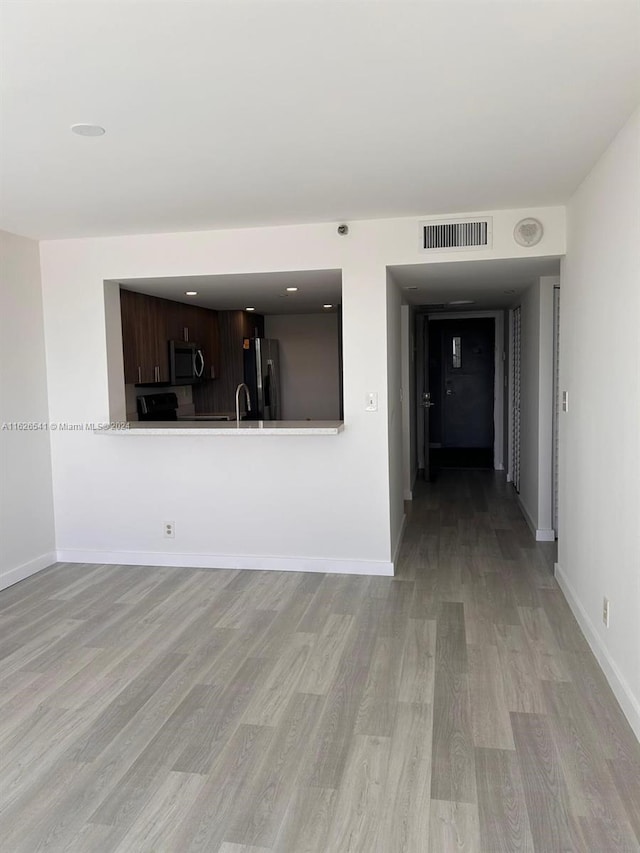 unfurnished living room featuring sink and light hardwood / wood-style floors