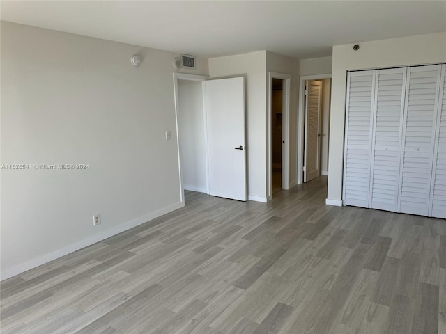 unfurnished bedroom with light wood-type flooring and a closet