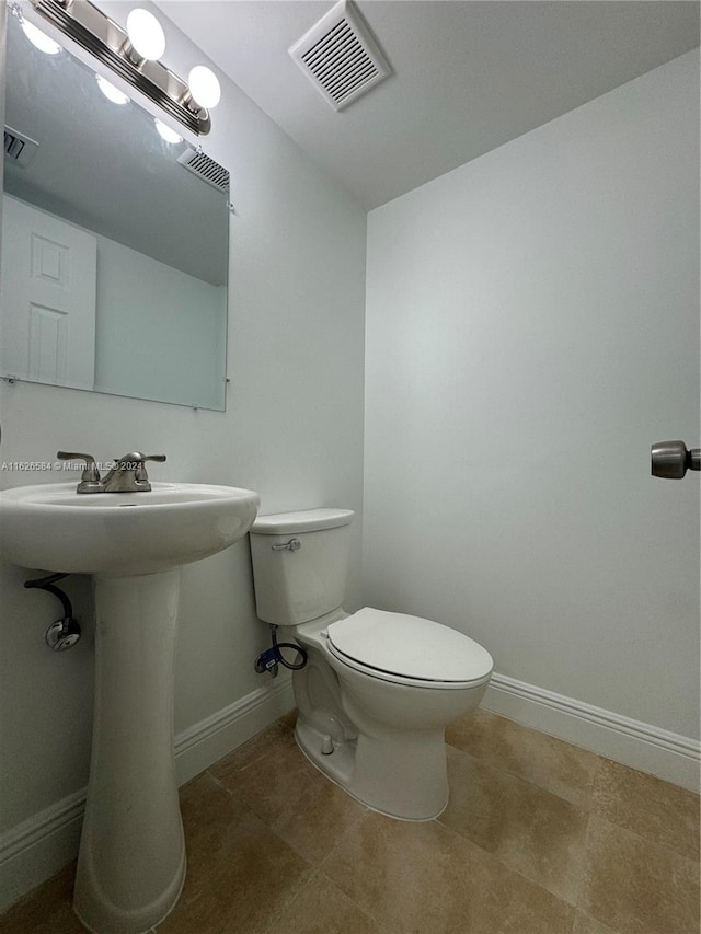 bathroom with toilet, tile patterned floors, and sink