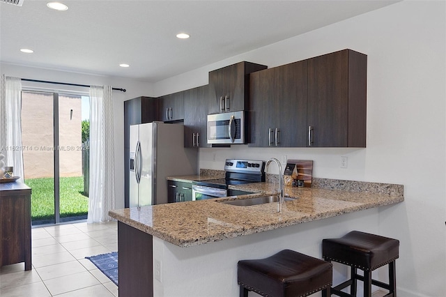 kitchen featuring light stone countertops, kitchen peninsula, stainless steel appliances, and a wealth of natural light