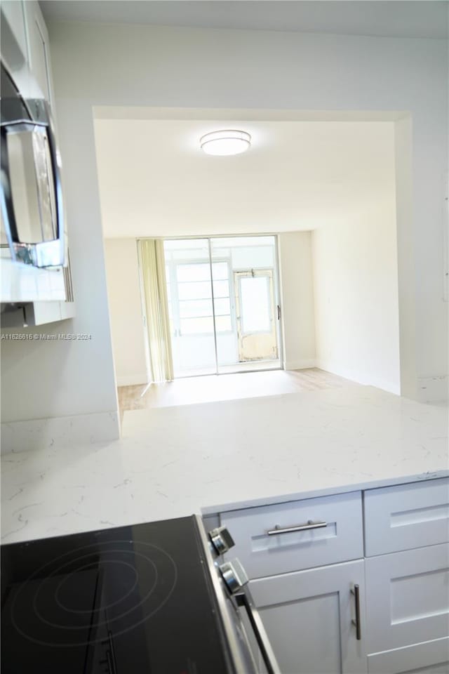 kitchen with white cabinets, light stone counters, and hardwood / wood-style floors