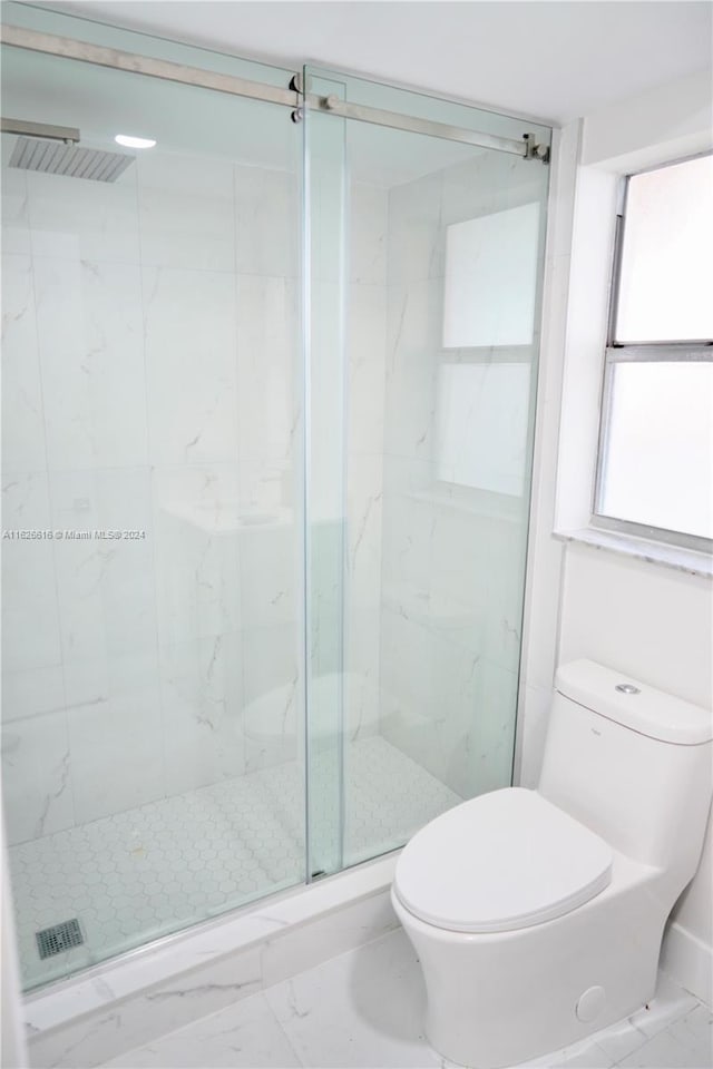 bathroom featuring a shower with shower door, toilet, and tile patterned flooring